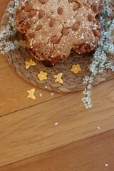 Fototapeta premium Sweet Easter cake named Colomba Pasquale (Easter dove) with mini decorations and hawthorn white flowers on wooden table. Italian traditional pastry