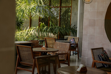 Fototapeta premium Seating area with wooden chairs and plants in a cafe