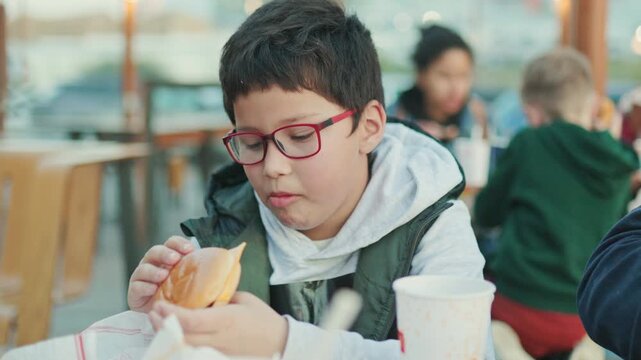 Young boy with glasses eating a cheeseburger