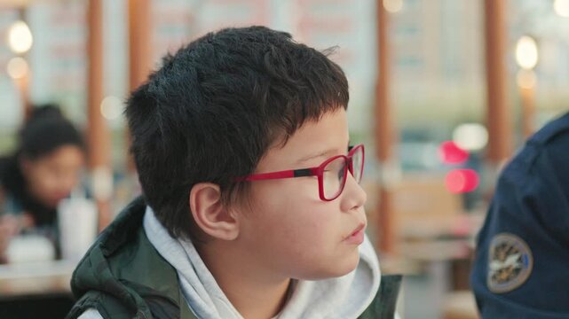 Young boy with glasses eating outdoors