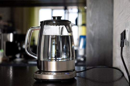 Transparent electric kettle with boiling water in the kitchen
