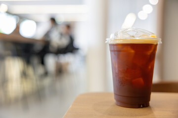Iced coffee in clear plastic cup with lid, resting on wooden surface