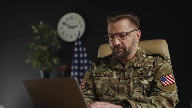 U.S. intelligence officer assessing threats while working on laptop in office