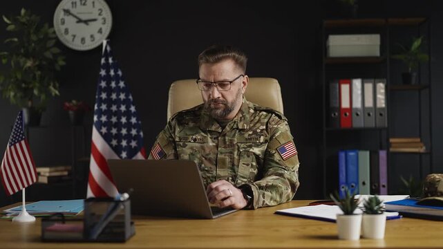 American military officer working on laptop in office, planning mission strategy