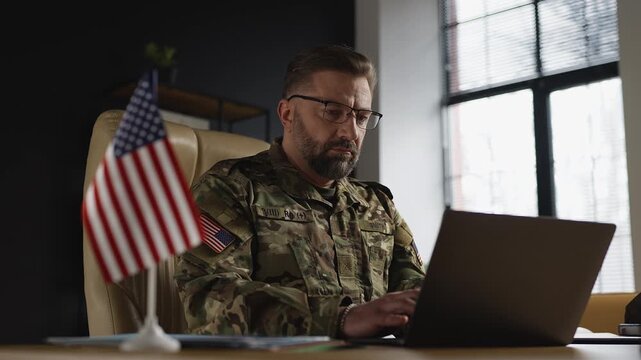 American army officer typing on laptop in office, planning defense operations