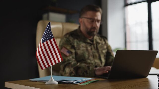 U.S. armed forces officer working on operational planning, typing on laptop