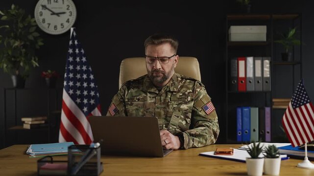 Portrait of middle-aged male intelligence officer working on laptop in office