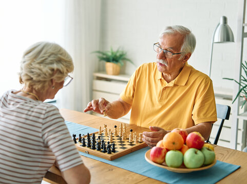 Portrait of a happy senior couple enjoying board game playing chess at home