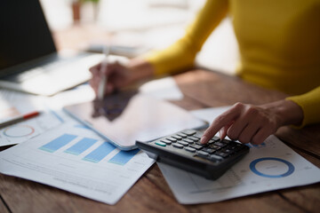 Fototapeta premium Person calculating numbers on a calculator, analyzing financial data on documents, and using a tablet, reflecting business planning and accounting tasks