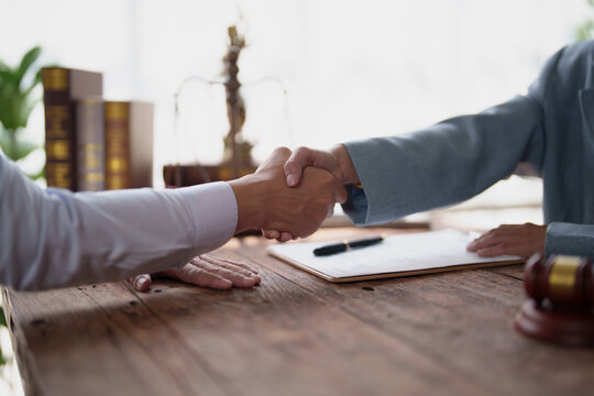 Legal professionals finalizing a business agreement with a handshake, symbolizing partnership, trust, and successful negotiation following a consultation in a law office setting