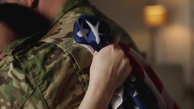 Happy wife with U.S. flag embracing soldier husband coming back home, reunion