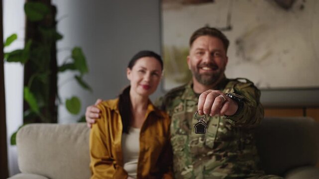 Smiling soldier man and his wife showing keys, housing program for military