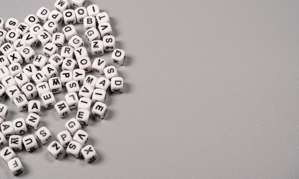 Colorful letter beads scattered on a grey surface for crafting