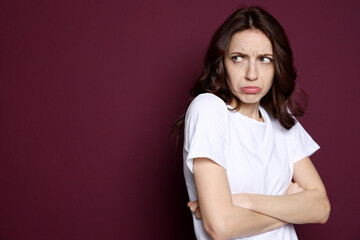 Obraz premium Portrait of resentful woman on burgundy background, space for text
