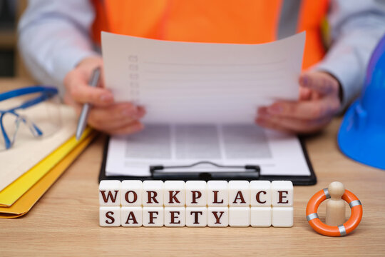 A professional in a bright safety vest studies important documents while surrounded by safety gear, emphasizing the need for safety awareness and compliance in the workplace.