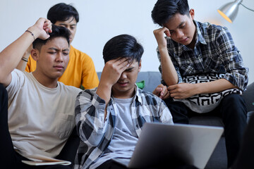 Fototapeta premium Group of Young Asian Men Looking Stressed and Frustrated While Working on Laptop