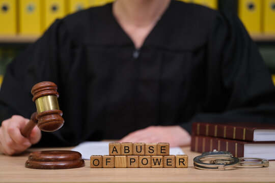 In a solemn courtroom, a judge prepares to deliver justice. The gavel is poised, and the phrase abuse of power is displayed prominently, emphasizing the gravity of the moment.