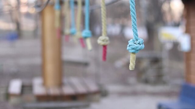 A row of vertically hanging strong ropes with securely tied knots at the ends. Fragment of a rope park. The end of the rope is wrapped with light protective tape. Selective focus