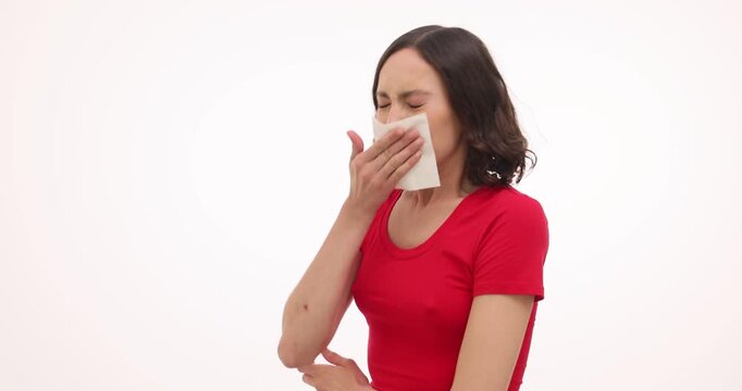 Woman sneezes into tissue bending forward during cold symptom. Sick female wipes nose showing allergy reaction while holding napkin tightly slow motion