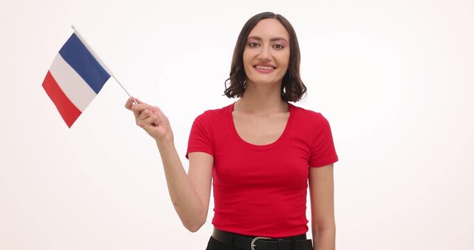 Woman smiles waving French flag for national celebration on white background. Female activist holds tricolor banner upright showing proud support