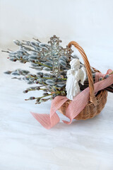Fototapeta premium Palm Sunday background. wicker basket with pussy willow branches, christianity cross, angel figurine on table. symbol of Easter, Palm Sunday holidays. prayer, faith, orthodox Church, religion concept
