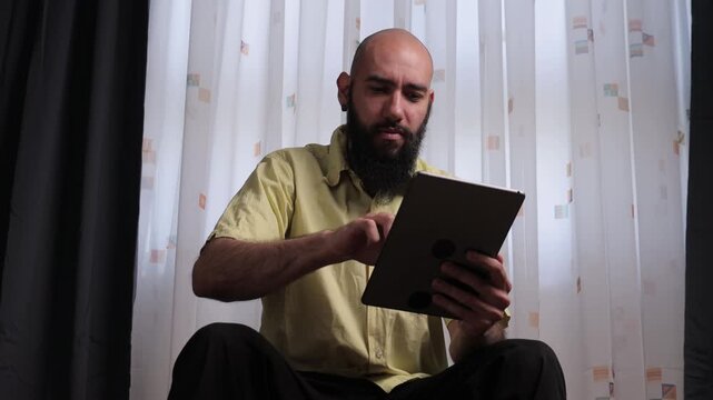 Successful bearded man celebrating a win on a tablet