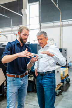 Two men discussing in a production hall with machinery