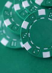 Naklejka premium Green casino poker chips on green gaming table close up. Few amount of green casino chips