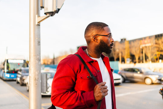 Stylish man in red jacket walking in busy city street