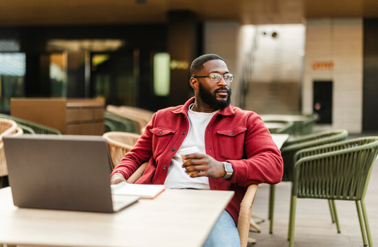 Man working on laptop with coffee outdoors at urban workspace
