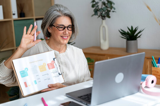 Woman presenting data during video call at home office workspace