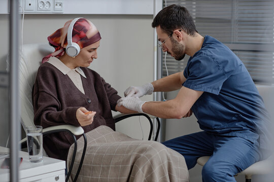 Doctor administering chemotherapy infusion to patient in clinic