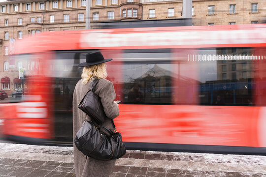 Young man waiting for tram in urban city using smartphone