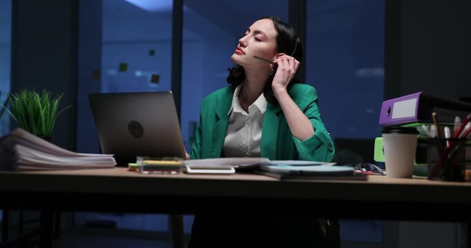 Tired call center female worker removes headset and closes laptop signaling end of workday. Lady closes laptop after finishing tasks. Slow motion