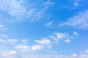 Fototapeta premium A serene clear blue sky filled with soft white cumulus and wispy cirrus clouds, creating a peaceful and bright atmosphere perfect for nature and weather backgrounds.
