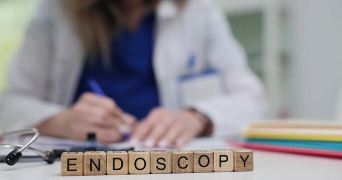 Wooden blocks spell word Endoscopy near stethoscope and medical tools. Doctor woman prepares referral explaining scope screening results clearly
