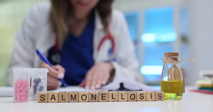 Wooden blocks spell word Salmonellosis near medicine jar and lab samples on table. Doctor woman writes note tracking foodborne infection symptoms