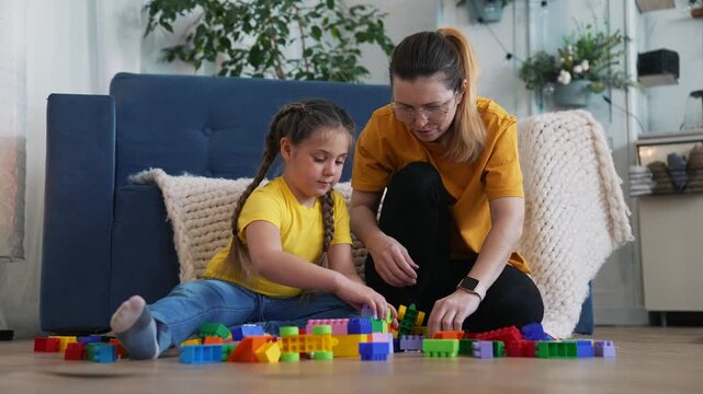 Mother and daughter play with colorful building block toy on home floor while parent guides child learning and creative play for family bonding and motor skill development through hands on building