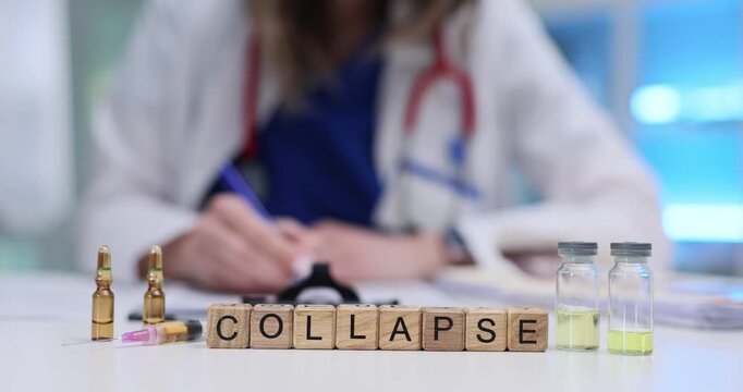 Doctor writes detailed recommendations in medical document. Wooden cubes carefully arranged to form word Collapse positioned near medicine ampoules