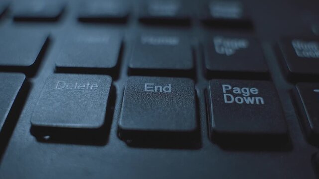 Finger clicking or pressing on End key button on computer keyboard in dark room at night. Coding or hacker pressing to finish task or terminate process. End concept dark web. Delete or remove key