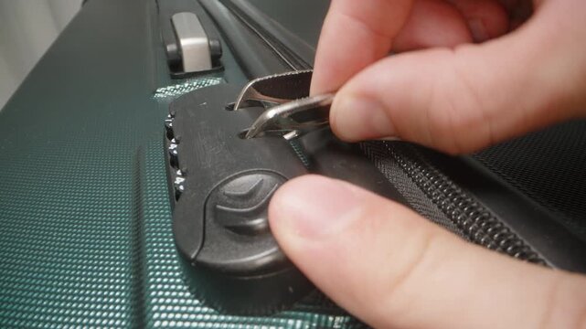 A Hand demonstrates how to use the combination lock, adjusting the code to unlock the zipper pulls on the suitcase.