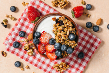 Yogurt bowl with granola and fresh berries for breakfast. Healthy breakfast, wholesome eating, homemade granola recipe concept. A top view flat lay. © magic_cinema