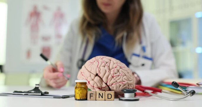 Neurologist studies medical history of patient focusing on documented symptoms and observations. Wooden cubes arranged on table form abbreviation FND