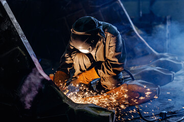 Welder cutting metal producing sparks for excavator bucket in industrial workshop © Parilov