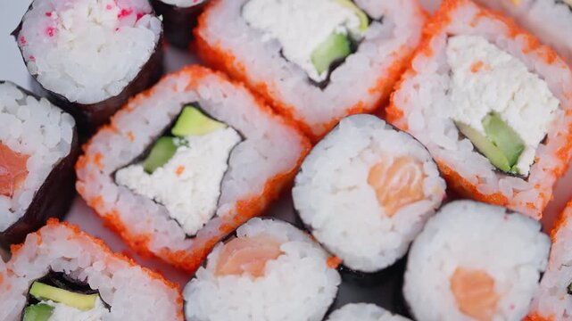 Bright sushi presentation. Colorful seafood and rice slices. Appealing salmon and avocado sushi closeup shot. Vivid arrangement of fish and rice rolls on display