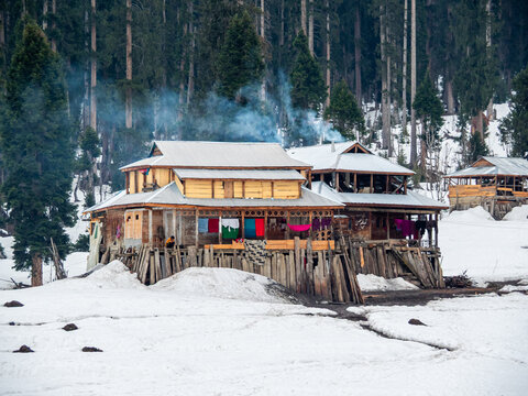 View of wooden houses stand out against the snowy landscape, smoke rises from chimneys in Arang Kel, Azad Kashmir, Pakistan.