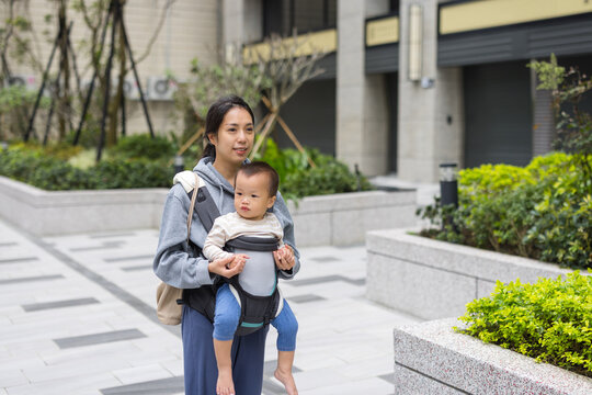 Mother walking with baby carrier in city