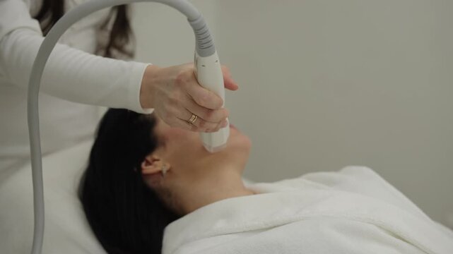 Professional cosmetologist performing microneedle rf lifting procedure on client face for skin rejuvenation, anti-aging effects, facial contouring in modern clinic. Concept of healthcare technology.