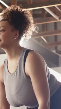 Vertical video: Leaning gripping barbell woman doing bent rows for power at gym in tank with watch