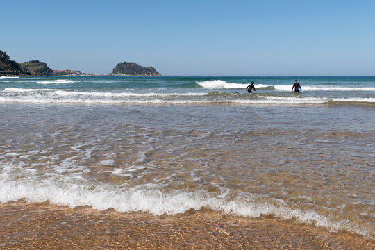 A couple of surfers on Zarautz Beach. Basque Country. Getaria in the background.